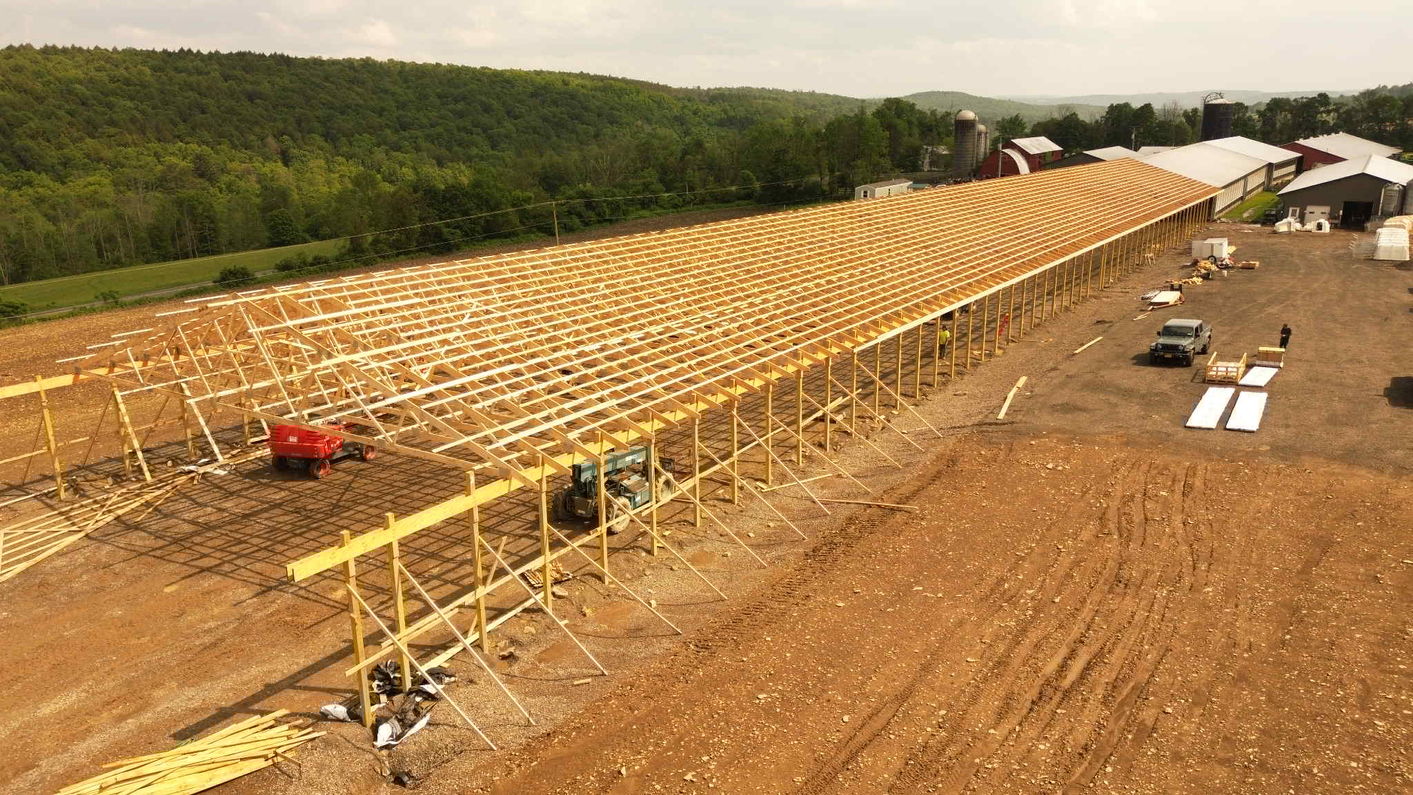Large wooden structure under construction with a rural landscape in the background