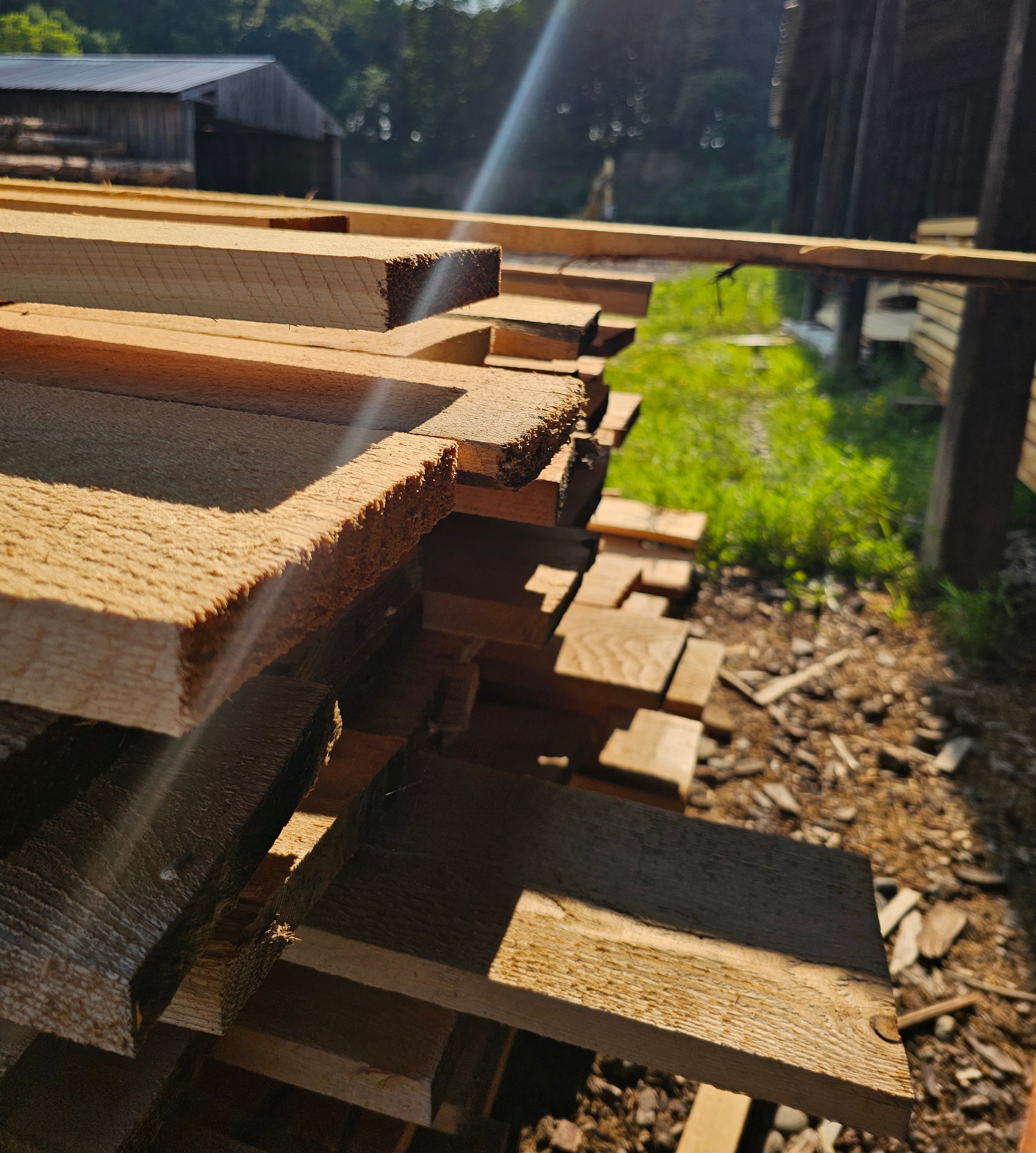 Stack of rough cut lumber outdoors with a blurred background