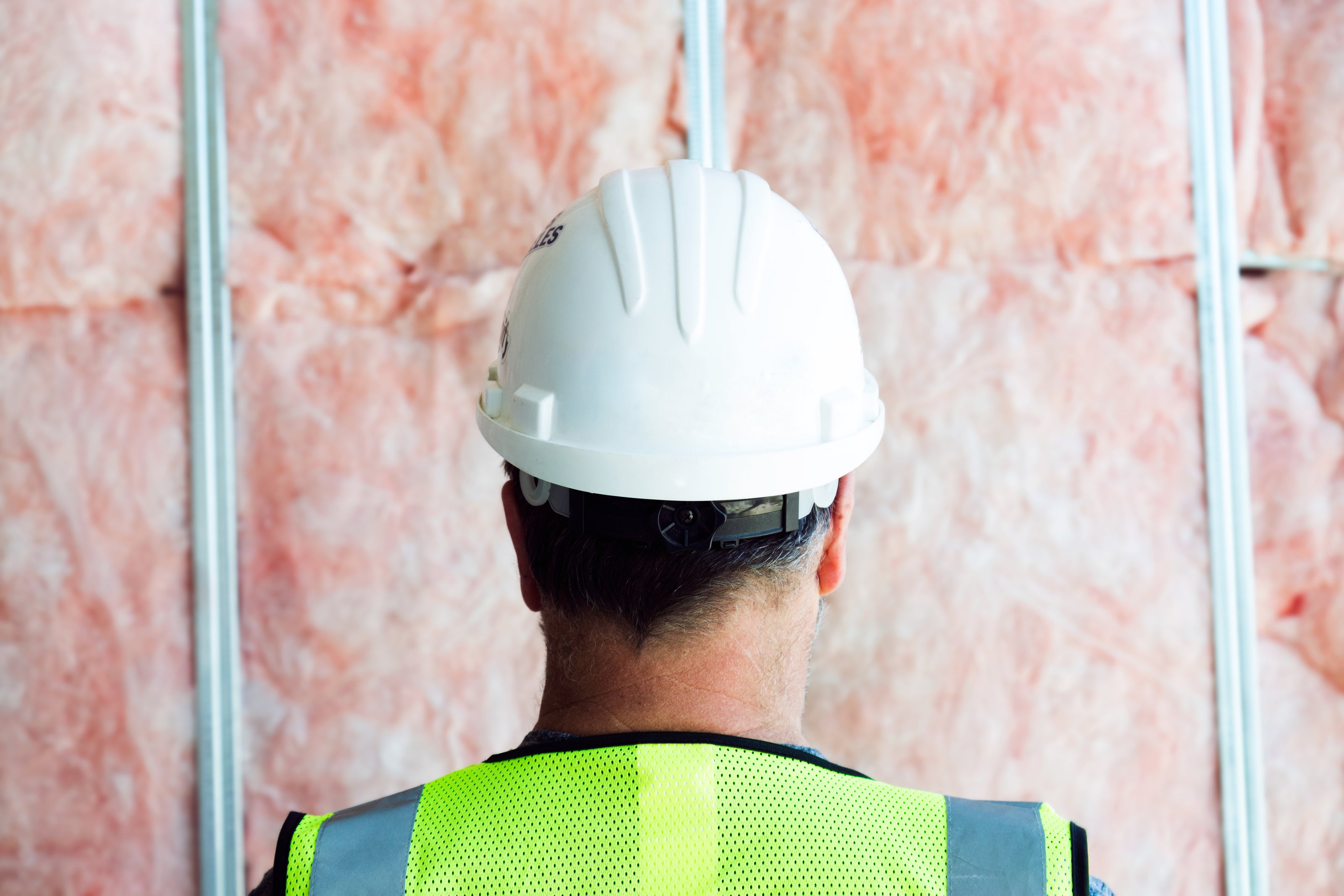 Construction Worker looking at framed wall filled with insulation